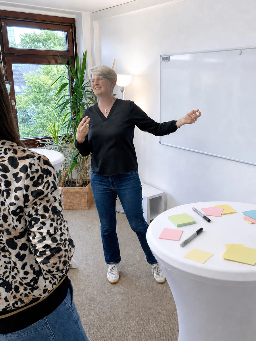 Anne Komp, stehend, bei einer Teamberatung.